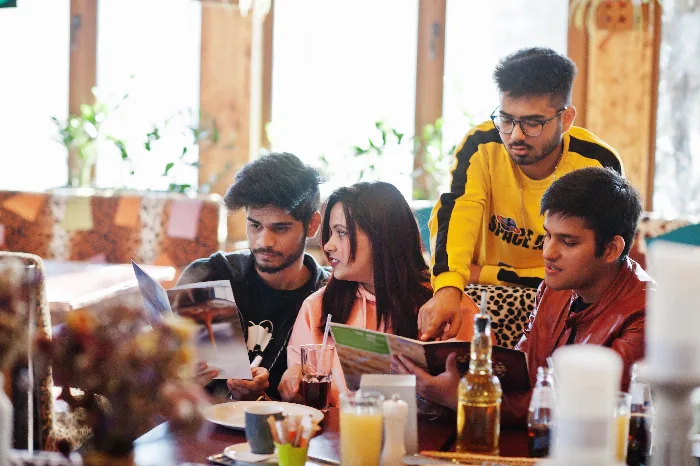 Group of international students smiling and sharing a meal together in the campus dining space